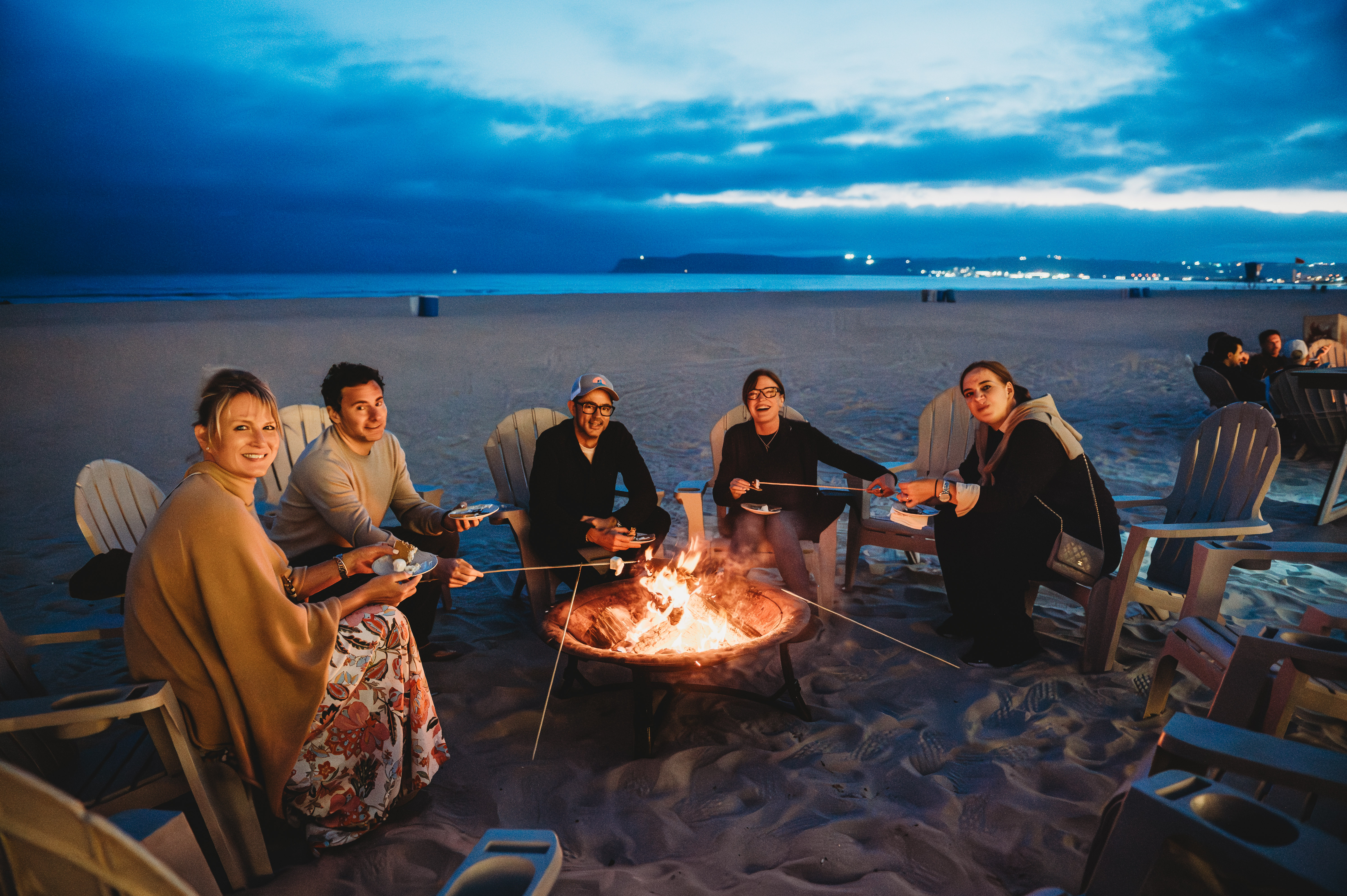 FIRE Summit 2026 attendees making s'mores around a Coronado beach firepit