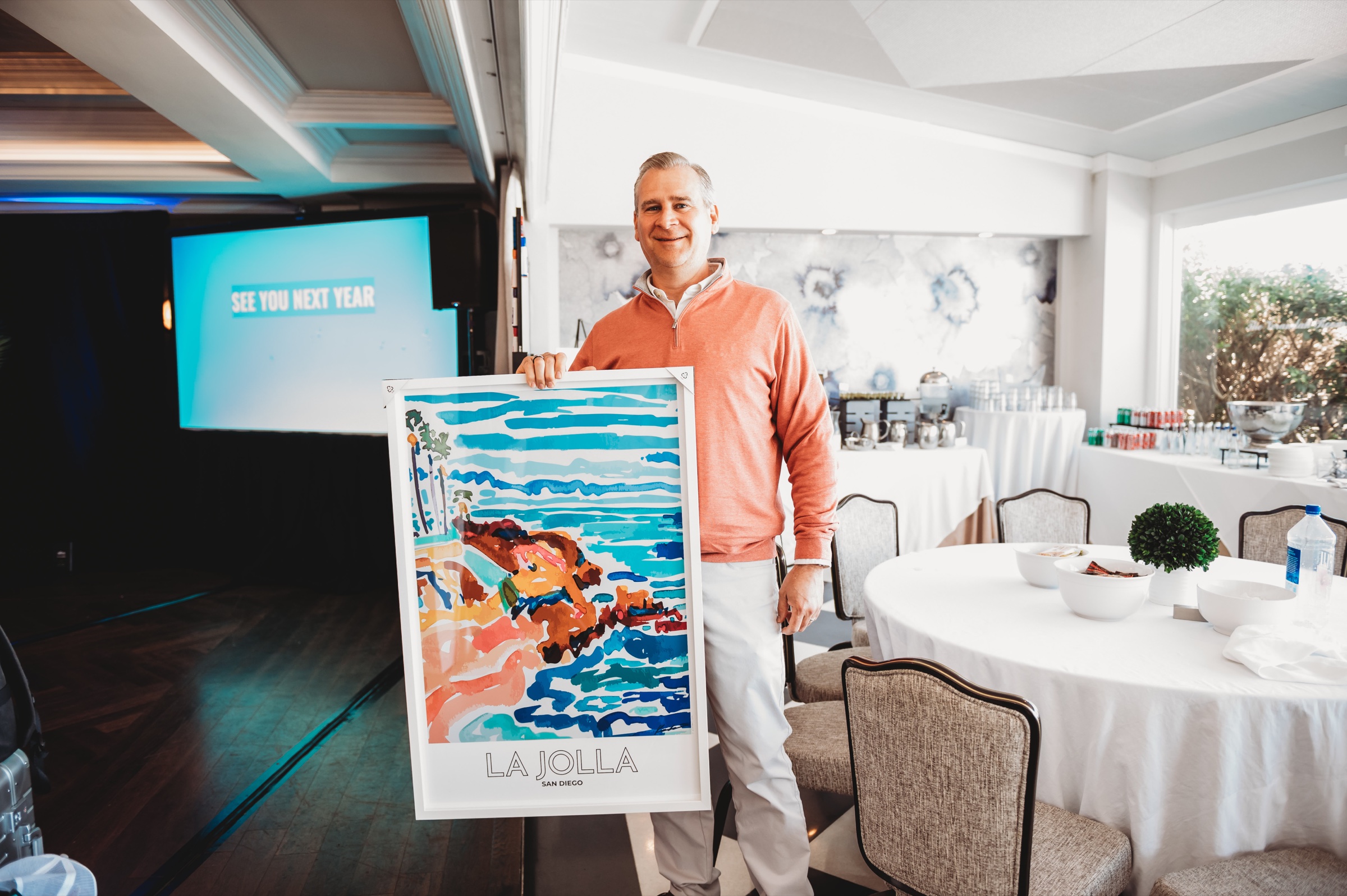 A FIRE Summit 2026 attendee holding a colorful La Jolla print